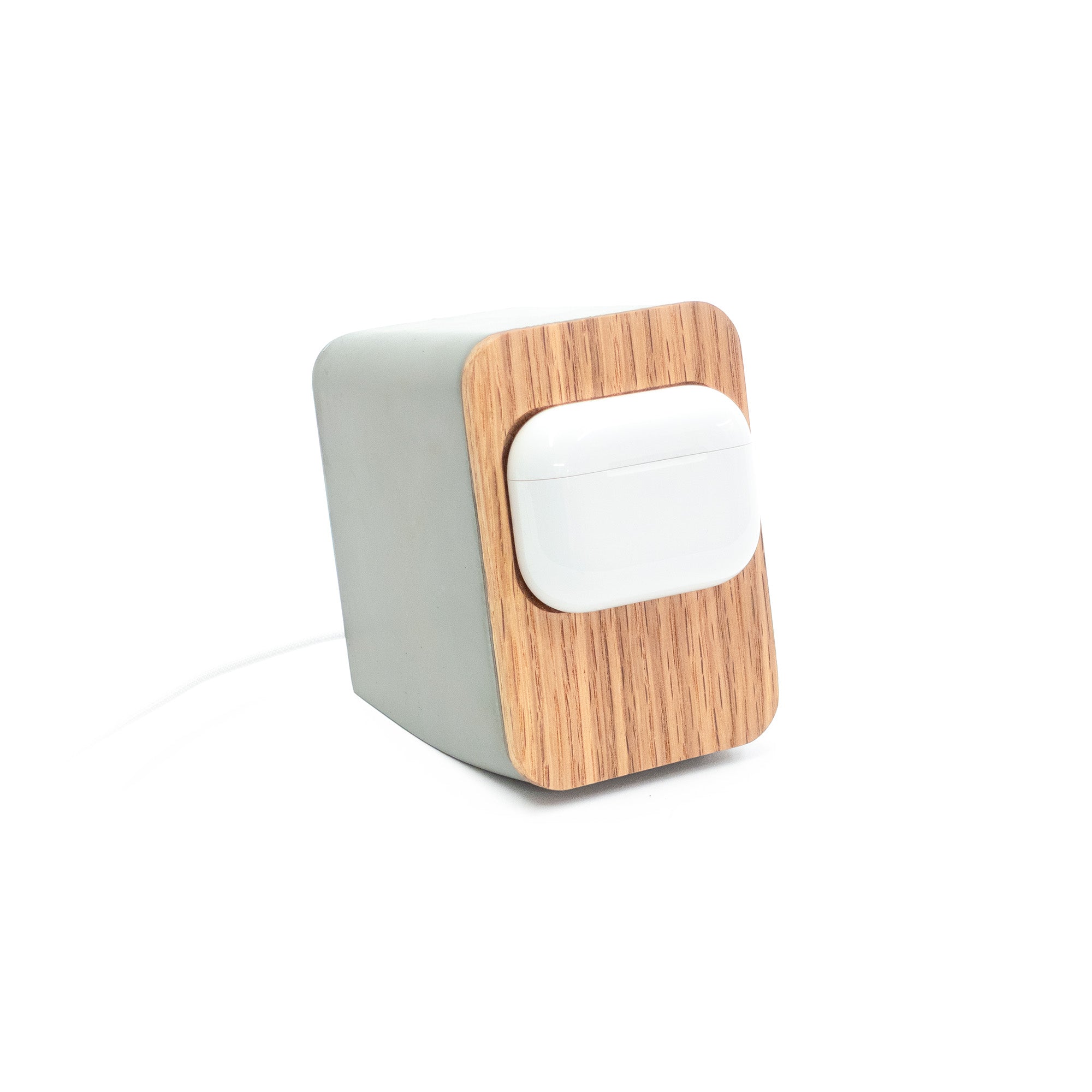 Angled view of Japandi-inspired concrete AirPods Pro MagSafe stand with thin white oak face and magnetic charging alignment.