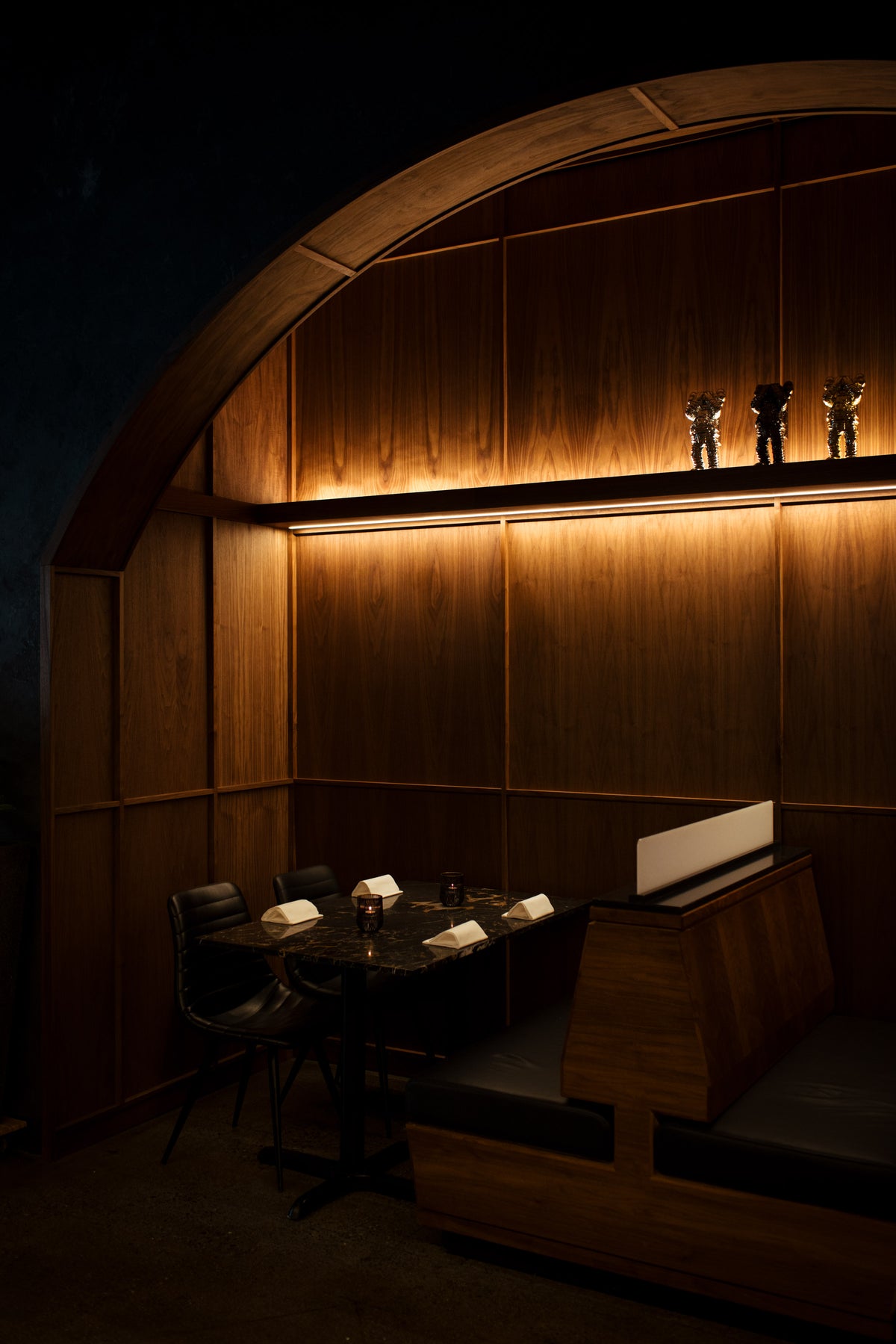 Custom walnut millwork and furniture installation including arched alcove, ribbed panels, wine storage, and seating at AnnaLena restaurant.