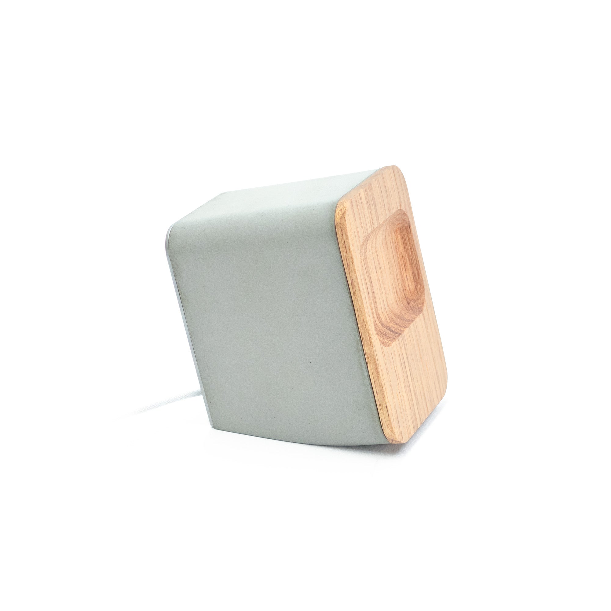 Architectural concrete AirPods Pro magnetic charging dock blending Brutalist mass with Scandinavian wood detailing.