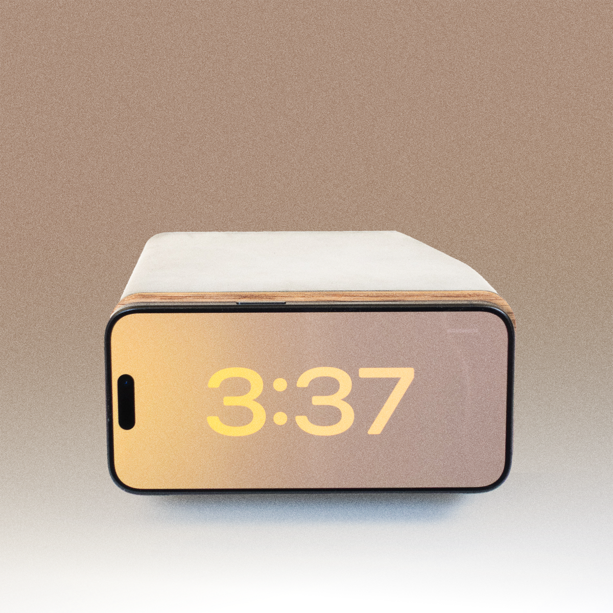 Angled view of iPhone in StandBy clock mode resting on white oak and concrete MagSafe dock, highlighting architectural form and material contrast.