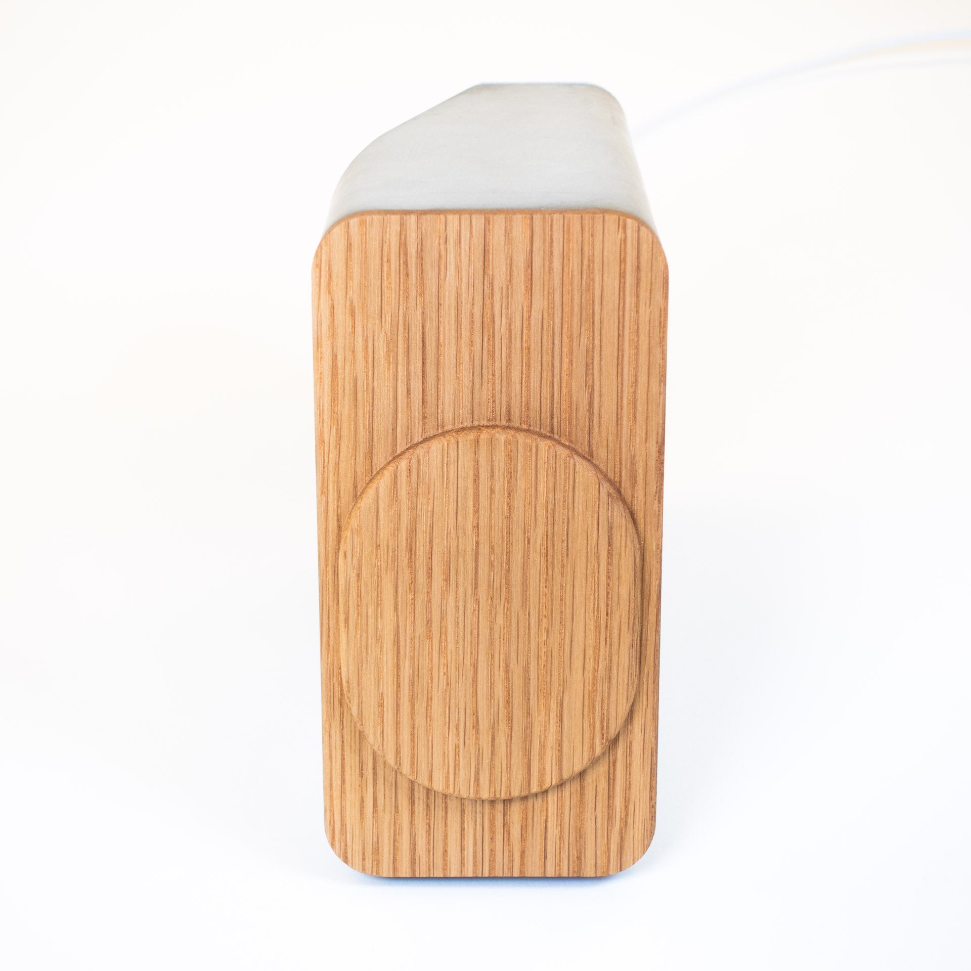 iPhone charging upright on modern MagSafe charger with concrete and wood base