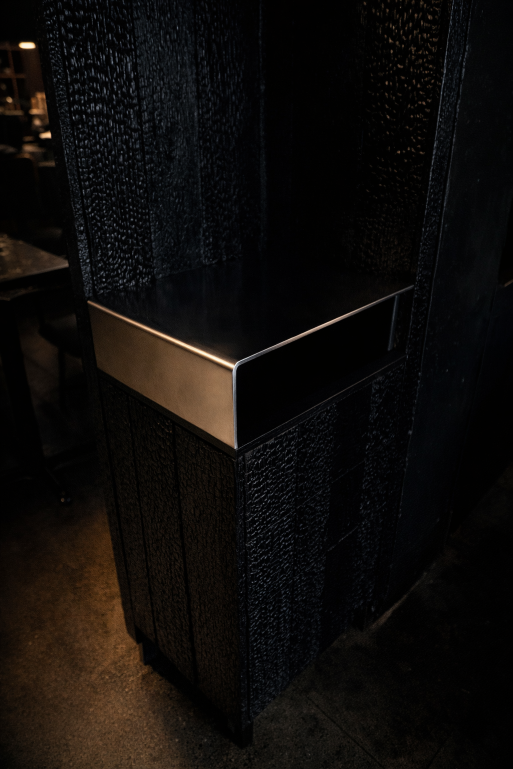 Stainless steel cubby detail integrated into custom Shou Sugi Ban furniture with concealed millwork construction.