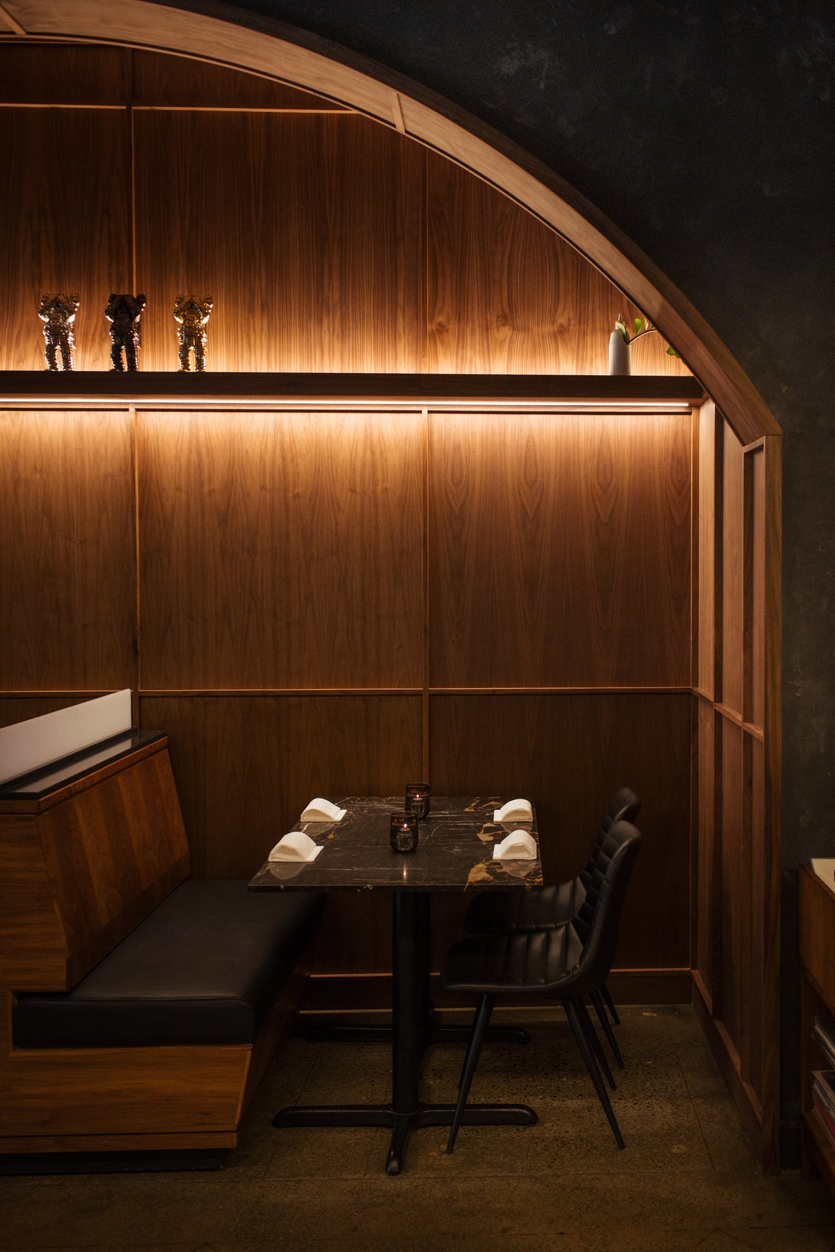 Walnut alcove set within a dark Venetian stucco wall, featuring recessed LED lighting and built-in seating at AnnaLena.
