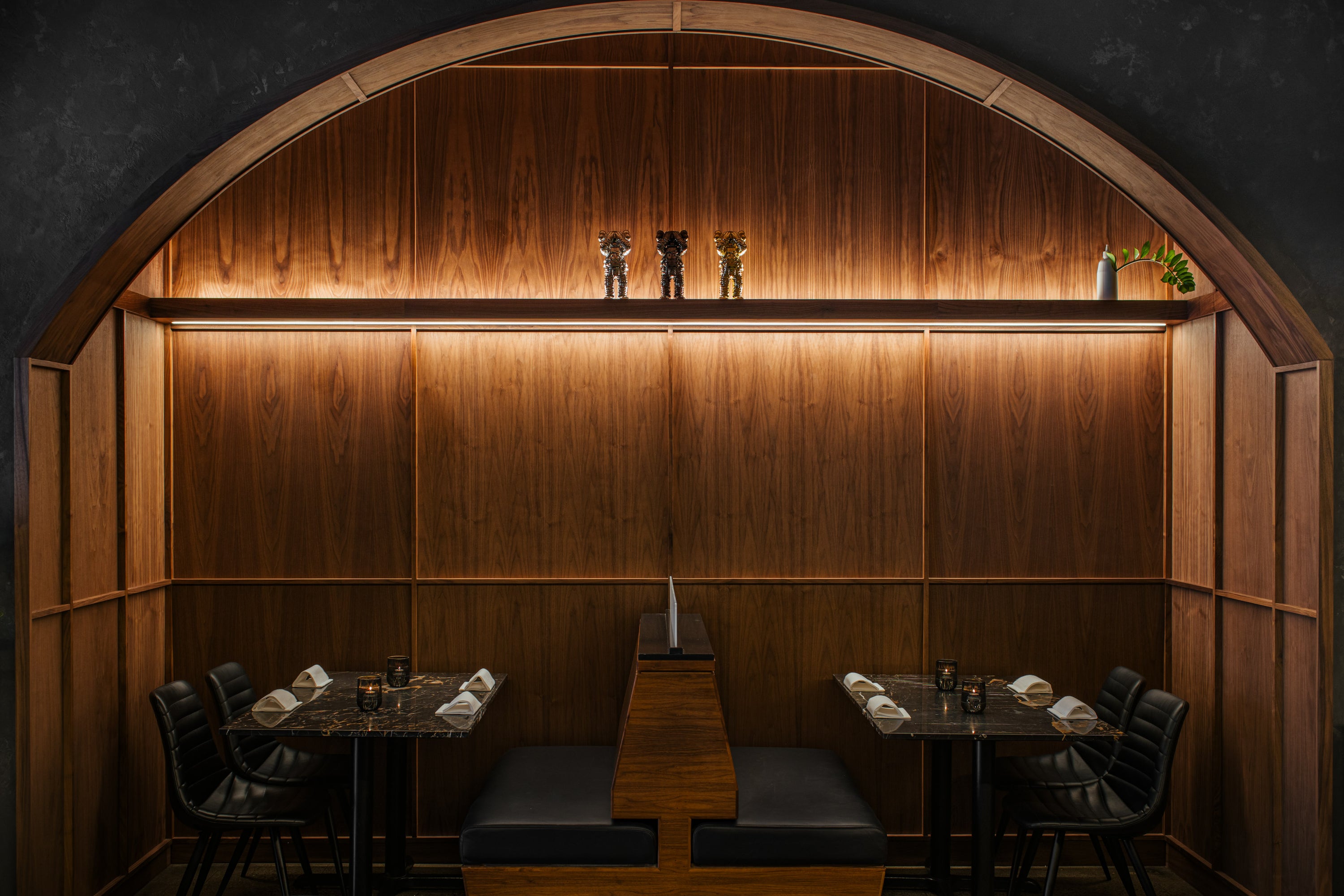 Walnut dining alcove with arched surround, recessed shelf lighting, ribbed panel walls, and integrated banquette seating in Vancouver.