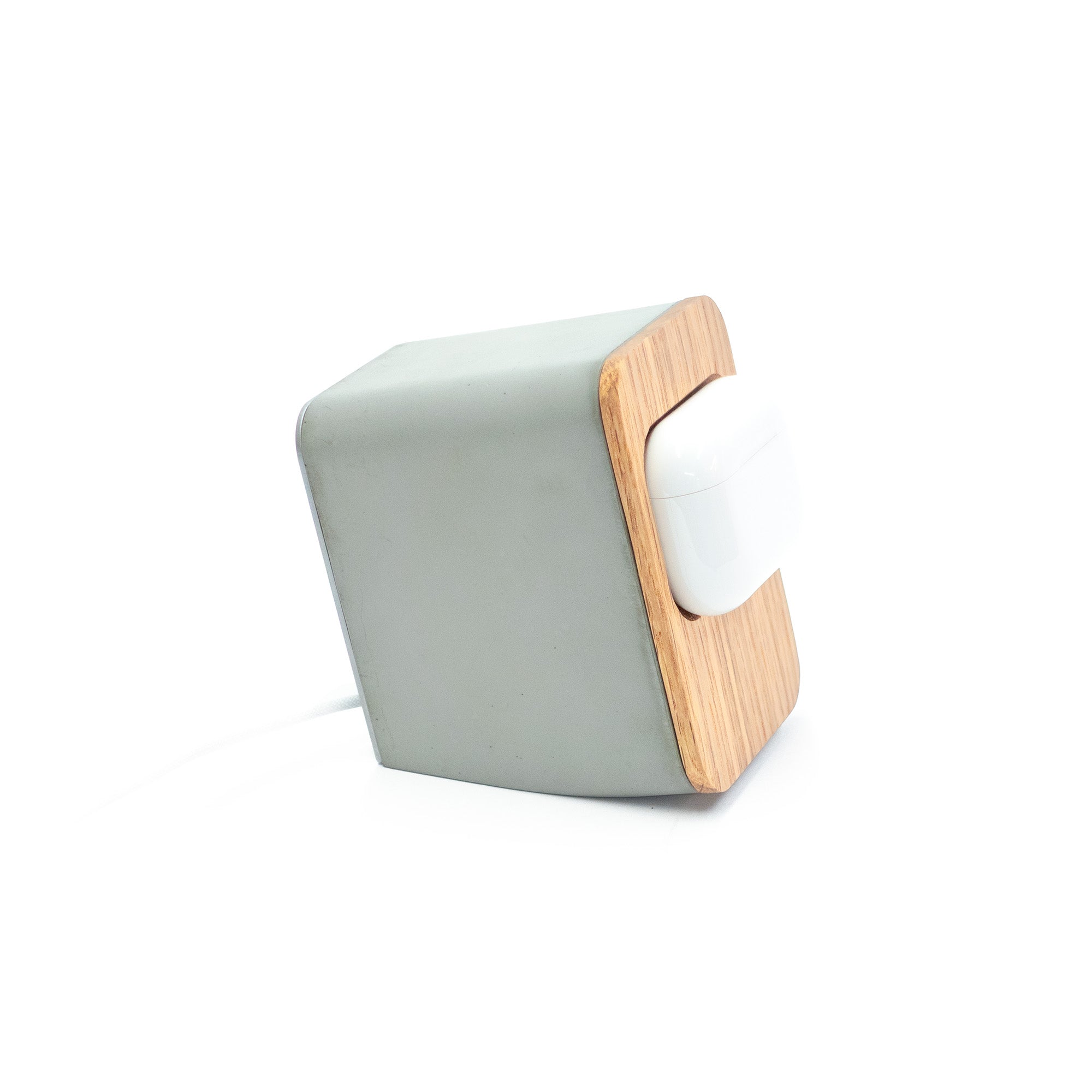 Close-up detail of recessed white oak dish concealing MagSafe charger inside a handcrafted concrete AirPods Pro stand.